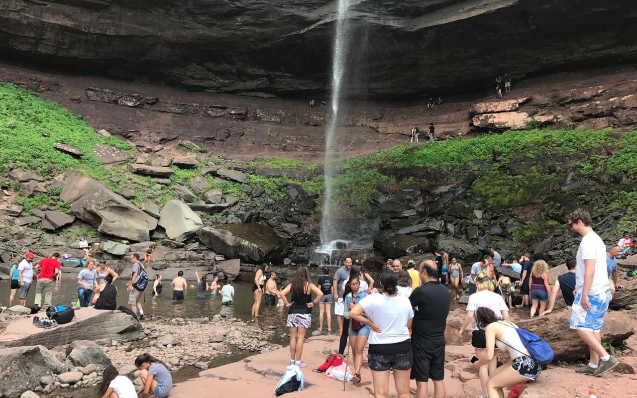 Crowded scene at Kaaterskill Falls, water falling onto rocks and many people in and around the water area. Photo source: NYS DEC/Ranger Dawson